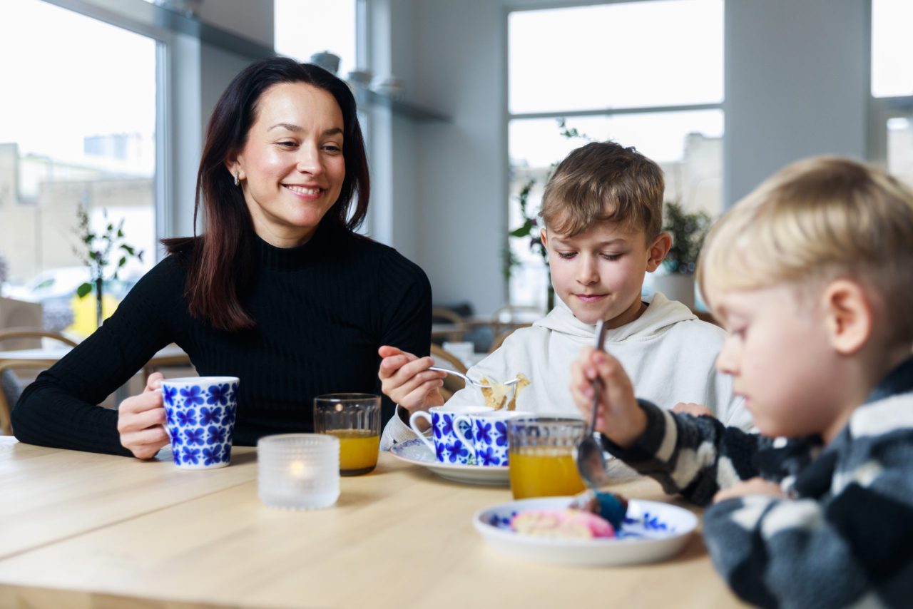 Glad kvinna och två barn fikar i kafét på Rörstrand Museum.